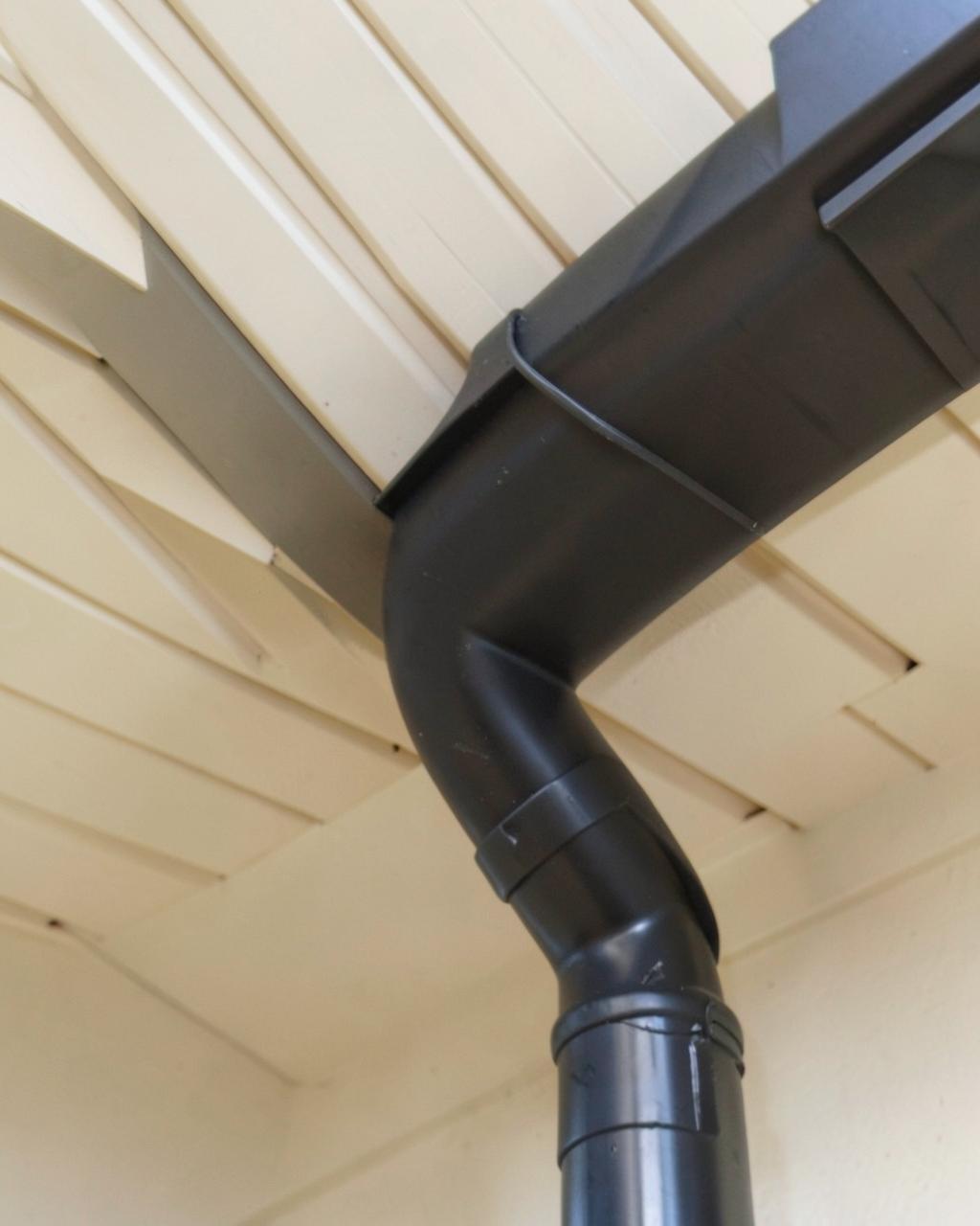 Dark seamless gutter and downspout against a soffit