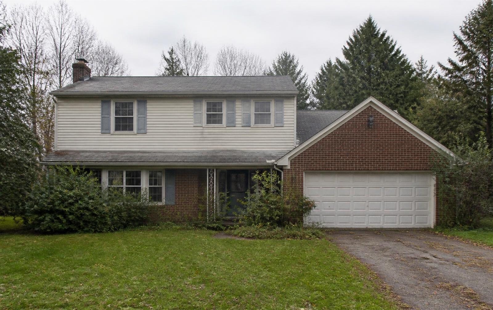 Dated suburban home exterior with worn roof and faded siding